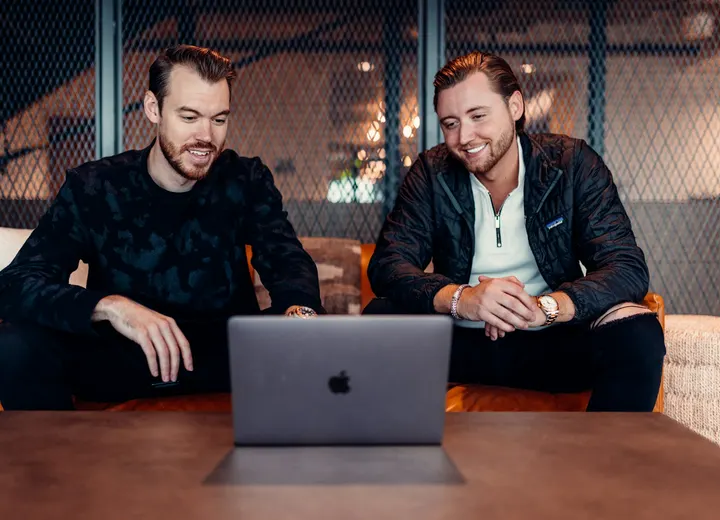 Two startup co-founders smiling while working together on a laptop