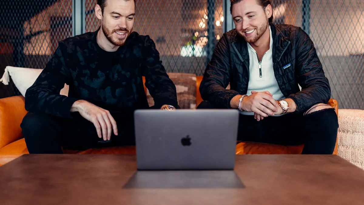 Two startup co-founders smiling while working together on a laptop