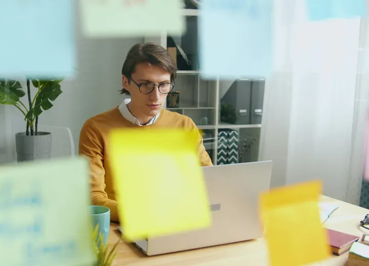 Entrepreneur brainstorming startup ideas at a laptop surrounded by colorful sticky notes