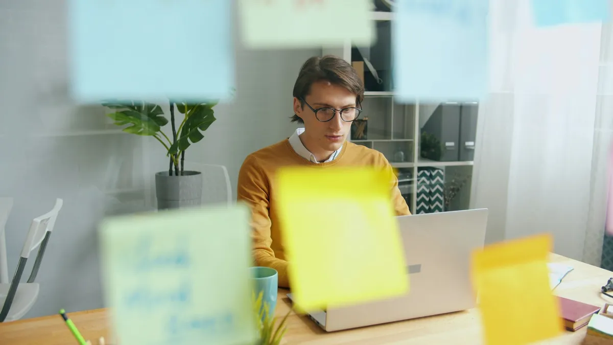 Entrepreneur brainstorming startup ideas at a laptop surrounded by colorful sticky notes