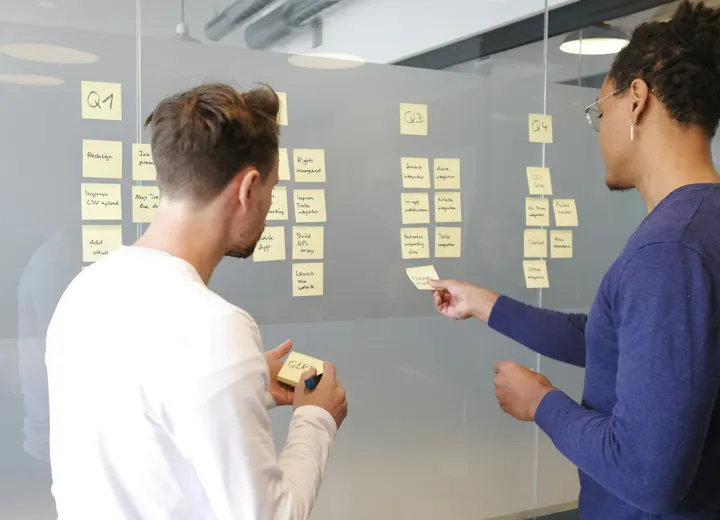 Two founders organizing customer research notes on a glass wall to validate a startup idea