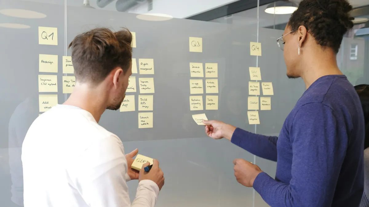Two founders organizing customer research notes on a glass wall to validate a startup idea